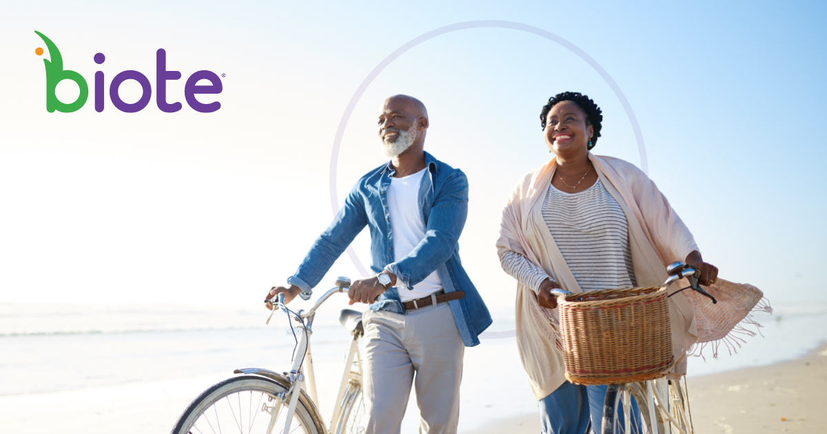 happy couple walks their bicycles on the beach